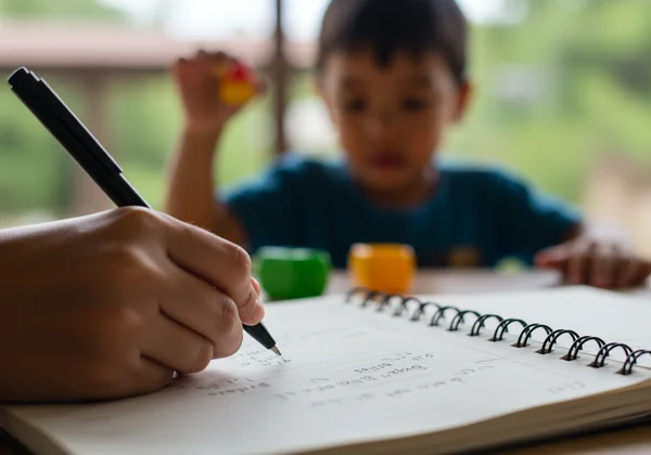 Parent documenting child's behaviors in a journal notebook